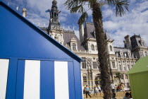 The Paris Plage urban beach. Young people playing beach volleyball behind beach huts in front of the Hotel de Ville Town Hall