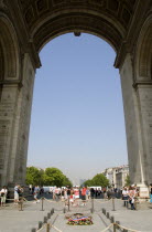 Tourists beside the Tomb of The Unknown Soldier under the main arch of the Arc de Triomphe in Place Charles de Gaulle with La Defence on the horizonDefense European French Western Europe