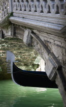 The Ferro at the bow of a gondola passing under a footbridge over a canal