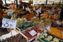 The vegetable market with vendor and shoppers beside the produce in the San Polo and Santa Croce district beside the Rialto Bridge on the Grand Canal