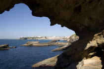 The Basque seaside resort on the Atlantic coast. The town and lighthouse seen through a rocky arch.