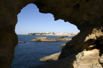 The Basque seaside resort on the Atlantic coast. The town and lighthouse seen through a rocky arch.