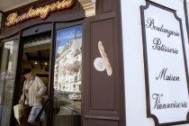 The Basque seaside resort on the Atlantic coast. Man leaving boulangerie bakery with bread in bags in the commercial centre of the town.