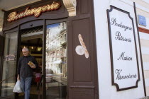 The Basque seaside resort on the Atlantic coast. Man leaving boulangerie bakery with baguettes under his arm in the commercial centre of the town.