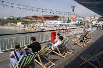 The West Beach from The Pier with the BICC Bournemouth International Conference Centre and Oceanarium in the distance. Tourists on deckchairs on the pier