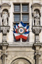 Formal display of French tricolour flags in a window beside statues on the facade of the Hotel de Ville Town HallEuropean Western Europe