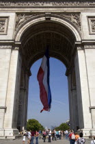 A French tricolour flag flying in the central arch of the Arc de Triomphe above tourists around the Tomb of The Unknown SoldierEuropean Western Europe