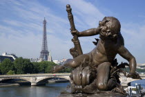 Bronze statue of a cherub on the Pont Alexandre III bridge across the River Seine with the Eiffel Tower in the distance European French Western Europe