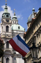 The National flag hanging from a balcony in Bridge Street with the Baroque Church of St Nicholas beyond in the Little QuarterPraha Ceska Eastern Europe European Religion