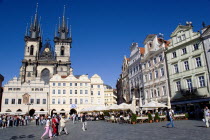 People seated at restaurant tables under umbrellas in the Old Town Square in front of the Church of Our Lady before Tyn with pedestrians walking across the squarePraha Ceska Eastern Europe European R...