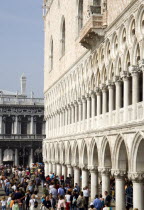 Tourist crowds pass below the quayside facade of the Doges Palace