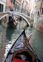 Gondolas carrying sightseeing tourists on a canal heading for a bridge in the San Marco district