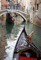 Gondolas carrying sightseeing tourists on a canal heading for a bridge in the San Marco district