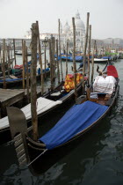 Gondolas moored by Molo San Marco with the Baroque church of Santa Maria della Salute on the Grand canal beyond on a misty day