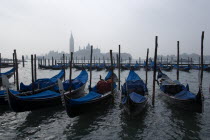 Gondolas moored by Molo San Marco with Palladios church of San Giorgio Maggiore beyond on a misty day