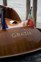 The stern  rear  of a water taxi called Grazia moored beside a jetty