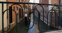 Gondolas in a narrow canal in the San Marco district seen through the iron railings of a bridge