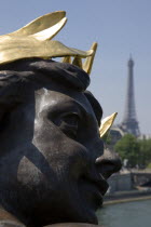 Face of a bronze figure on the Pont Alexandre III bridge with the Eiffel Tower in the distanceEuropean French Western Europe