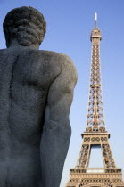 Stone sculpture of a seated man in the Trocadero Gardens with the Eiffel Tower in the distanceEuropean French Western Europe