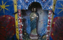 Religious statuette in blue painted shrine with feathers in coloured paper.