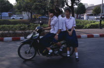 Speeding moped carrying three girls dressed in uniform with the driver talking on a mobile phone.Asian Cell Cellular Prathet Thai Raja Anachakra Thai Siam Southeast Asia Siamese Asian Cell Cellular...