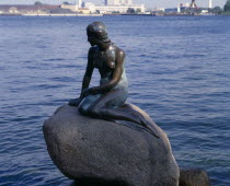 The Little Mermaid bronze statue sitting on a rock in calm water Danish Danmark Northern Europe Scandinavia