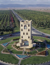 Elevated view over men working in grounds of clock tower with lines of palms behind and desert in distance beyond.Male Man Guy Middle East Omani United Arab Emirates Al-Imarat Al-Arabiyyah Al-Muttahi...