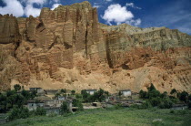 Summer landscape.  Adobe village housing and cultivated land at foot of steep  eroded cliff.  farming Asia Asian Nepalese Scenic Agriculture Farming Agraian Agricultural Growing Husbandry  Land Produ...