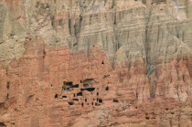 Ancient cave dwellings in steep  eroded grey and orange coloured cliff face.erosion shelter home Asia Asian Colored Gray History Nepalese Scenic