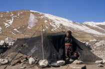 Tibetan nomad encampment on the high plateau  woman and child looking out from entrance of tent with light covering of snow on mountainside behind.shelter home camp Asia Asian Kids Nepalese Children...