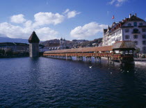 Kappelbrucke flower decked covered bridge spanning across The River Reuss. Adjoining the bridge is the Wasserturm 13th Century octagonal tower The bridge has been restored after a fire in 1993 Europ...