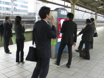 Yurakucho - the smokers corner on the JR train platform  men and young woman smokingAsia Asian Japanese Nihon Nippon Female Women Girl Lady Male Man Guy Female Woman Girl Lady Male Men Guy Immature