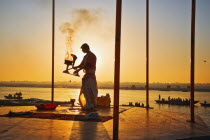 Performing the Ganga Aarti Ceremony at dawn over the River Ganges.IndiaVaranasiUttar PradeshAarti CeremonyRiver GangesFaithHinduHinduismTraditionDawnPerformHolySacredSunriseTravelTouri...