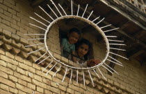 Children looking out of a window framed by the sun symbol of the Communist Party of Nepal- United Marxist LeninistsAsia Asian Nepalese Kids