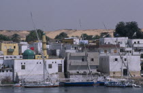 Nile River Nubian Village with boats moored on water next to waterfront buildings.African Middle East North Africa