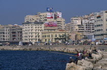 Corniche Waterfront . Men and boys fishing from rocks over the sea next to the promenade. Overlooked by tall buildings behindEl CornicheAfrican Middle East North Africa Male Man Guy Male Men Guy