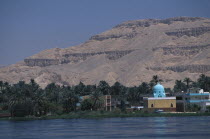 View across the River Nile towards a Mosque on the West Bank with a turquoise domed roof amongst dense palm treesAfrican Middle East North Africa Religious Scenic Religion