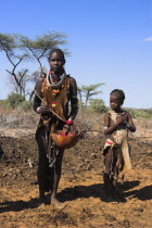 Dombo village  Child watching Hamer lady stirring cows bood ready for drinking