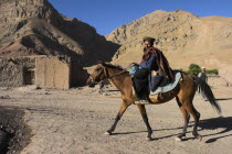 Aimaq man riding horse   The Aimaq are semi nomadic people who move out of their mud house villages after spring and live in yurts to tend their flocks before moving back to their houses in winter