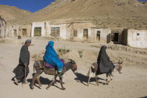 Man walking behind women on donkeys