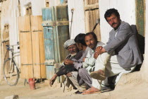 Men sit outside shop in early morning sunshine