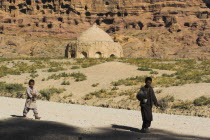 Boys walk past tomb near empty niche where the famous carved Budda once stood  destroyed by the Taliban in 2001