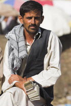 Money changer sits on rug on walls of Kabul river