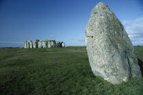 View across the grass on Salisbury Plain toward the standing stones with a large stone in the foreground