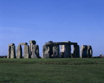 View across the grass on Salisbury Plain toward standing stones with visitors at base