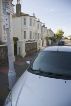 View over car bonnet parked next to lamp post with Permit holders only parking sign in residential street.