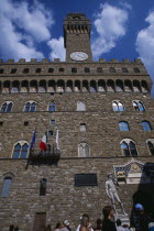 Piazza della Signoria. Palazzo Vecchio entrance and bell tower with a replica of the statue of David by Michelangelo Tourists gathered around the base.