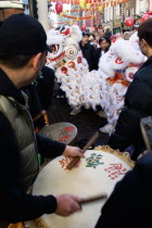 Lion Dance troupe and musicians performing in Wardour Street amongst the crowd outside restaurants during Chinese New Year celebrations in 2006 for the coming Year of The Dog