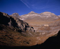 View at north east end of valley towards mountains of Las Tres Sorores and peak of Monte Pedido  3355m .  Trees in foreground and clearly visible coloured rock strata.