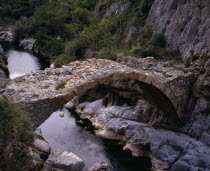 Clue de la Fou .  Roman bridge across the River Algy south of St Paul de Fenouillet.  Trees and eroded rocks overhanging rippled water.